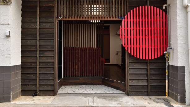 A doorway with a red circular design, a wooden door, and a tiled floor. - Machi de kurasu Tengachaya-1 (Osaka)