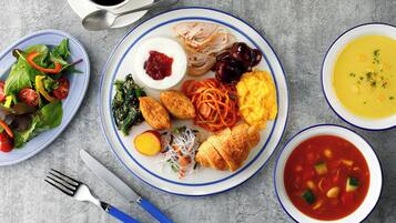 A table with various dishes including a salad, a plate with eggs, vegetables, and a bowl of soup.