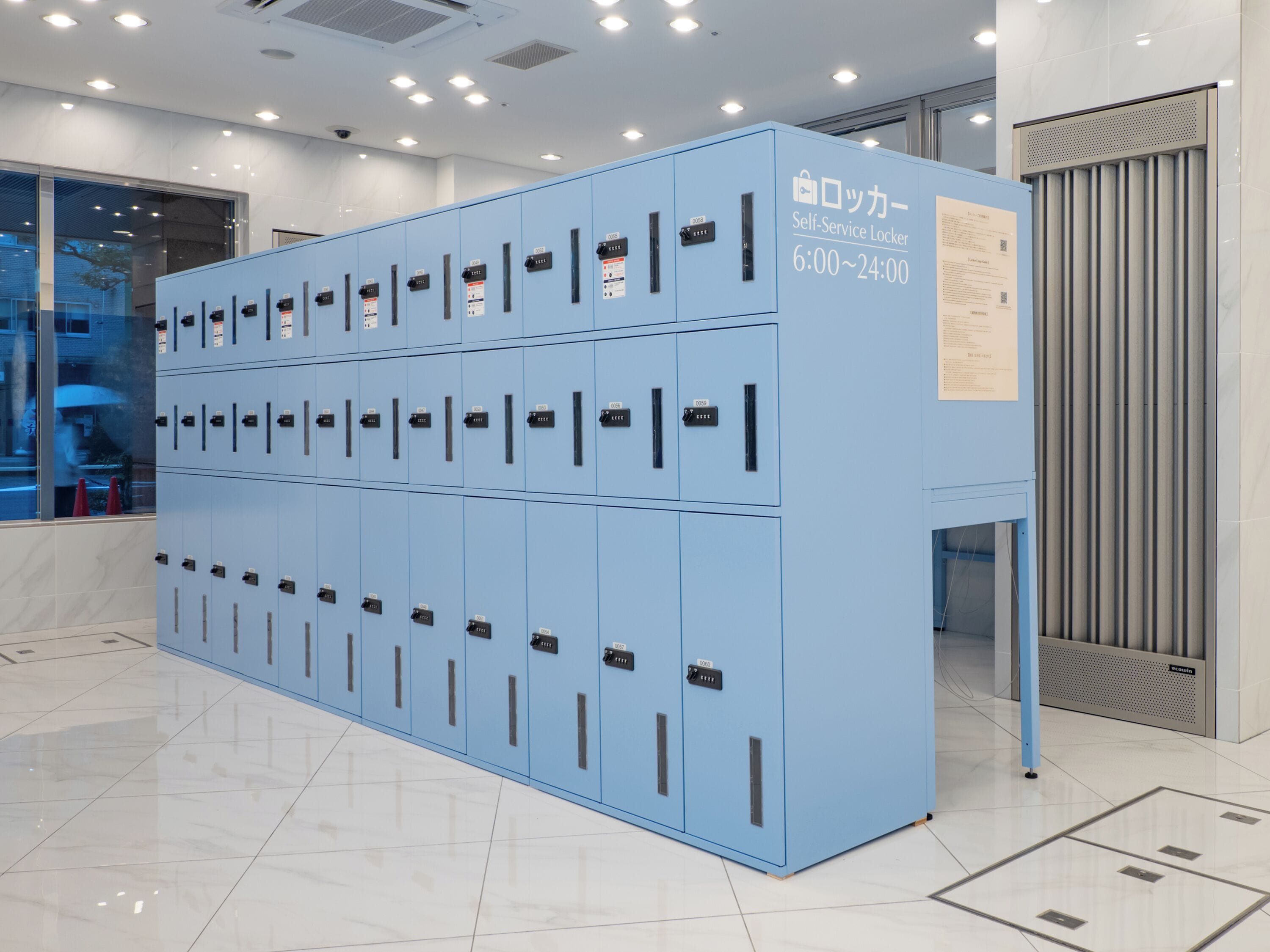 A row of blue self-service lockers with a sign indicating 24-hour access.