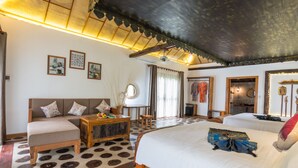 Une pièce spacieuse avec un grand lit, un canapé, une table basse en bois et un ventilateur de plafond.