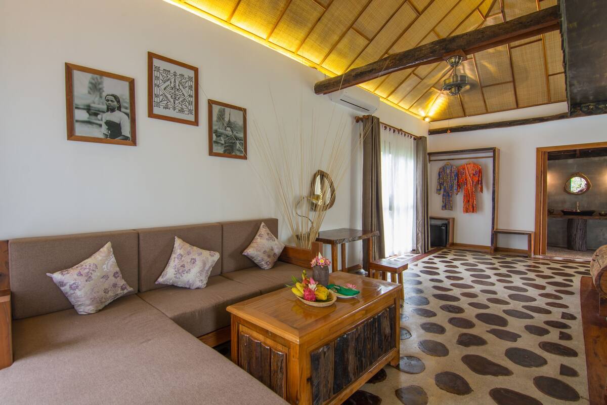 Un salón con un sofá, una mesa de centro con objetos decorativos, un suelo estampado y obras de arte en la pared.