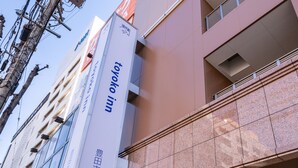 A hotel sign with Japanese text, indicating it is a hotel named "Tokyo Inn" located in "Toyoda City".