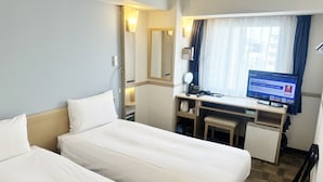 Une chambre d’hôtel avec deux lits, un bureau, un ordinateur et une fenêtre avec des rideaux.