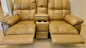 Un canapé en cuir marron avec un repose-pieds et des porte-gobelets.