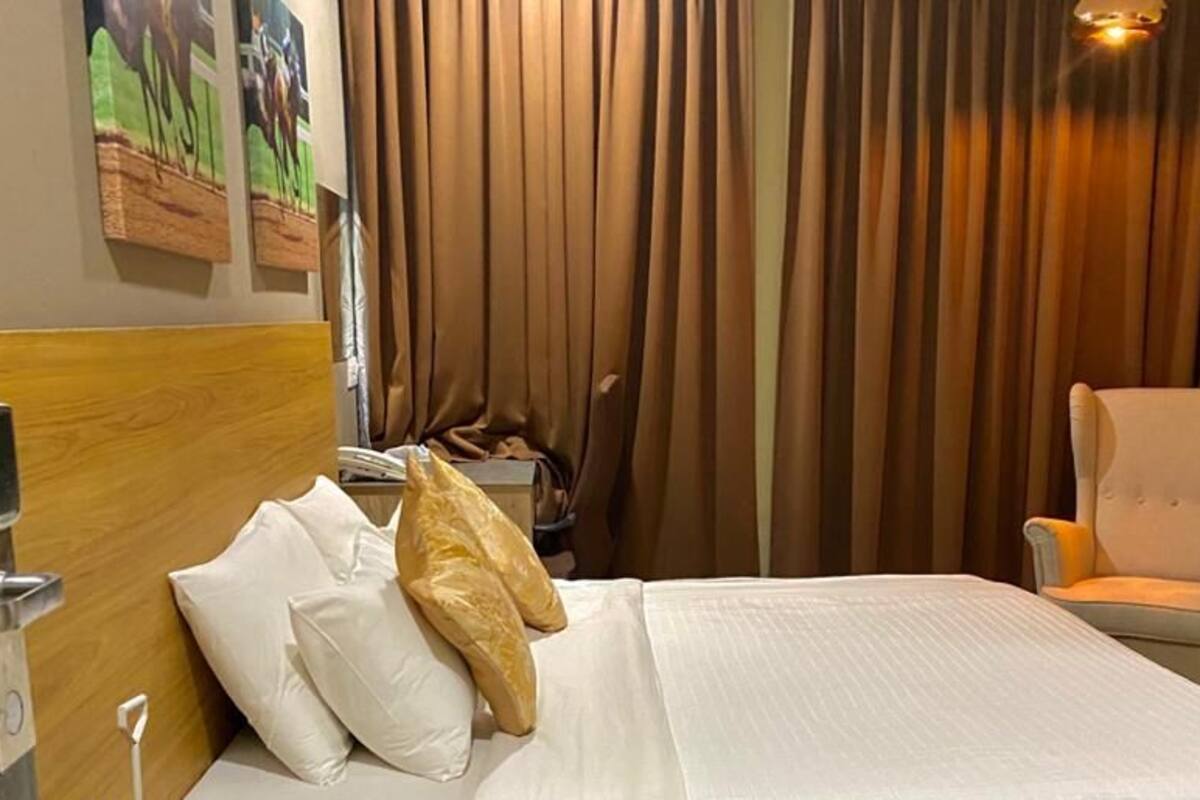 Une chambre d’hôtel avec un lit, une chaise, une télévision et des rideaux.