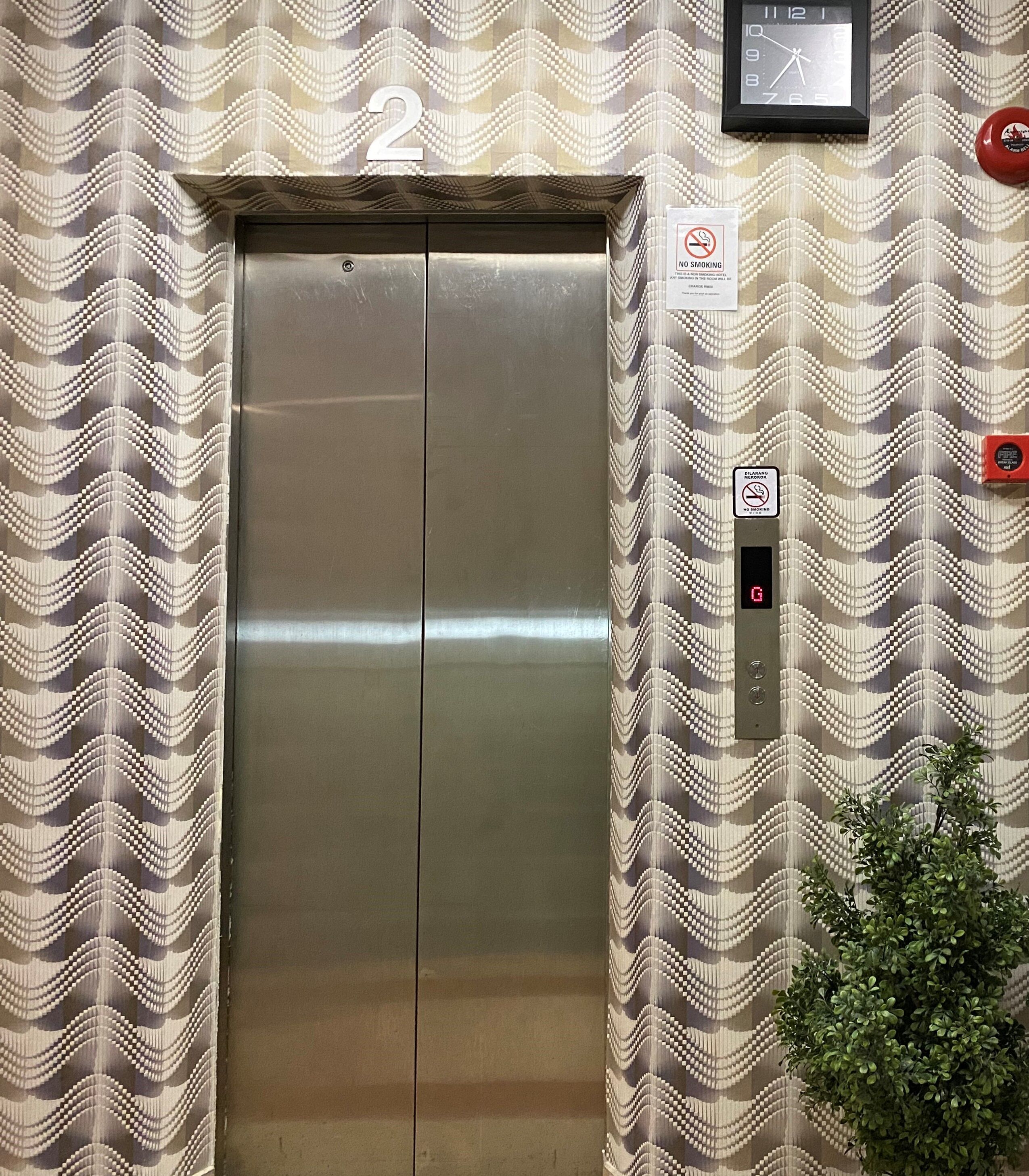 An elevator with a metallic finish, number 2, and a no-smoking sign on the wall.