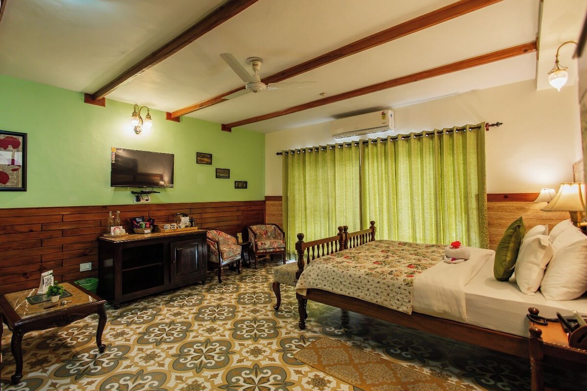A hotel room with a wooden bed, green curtains, a television on the wall, and a patterned floor.