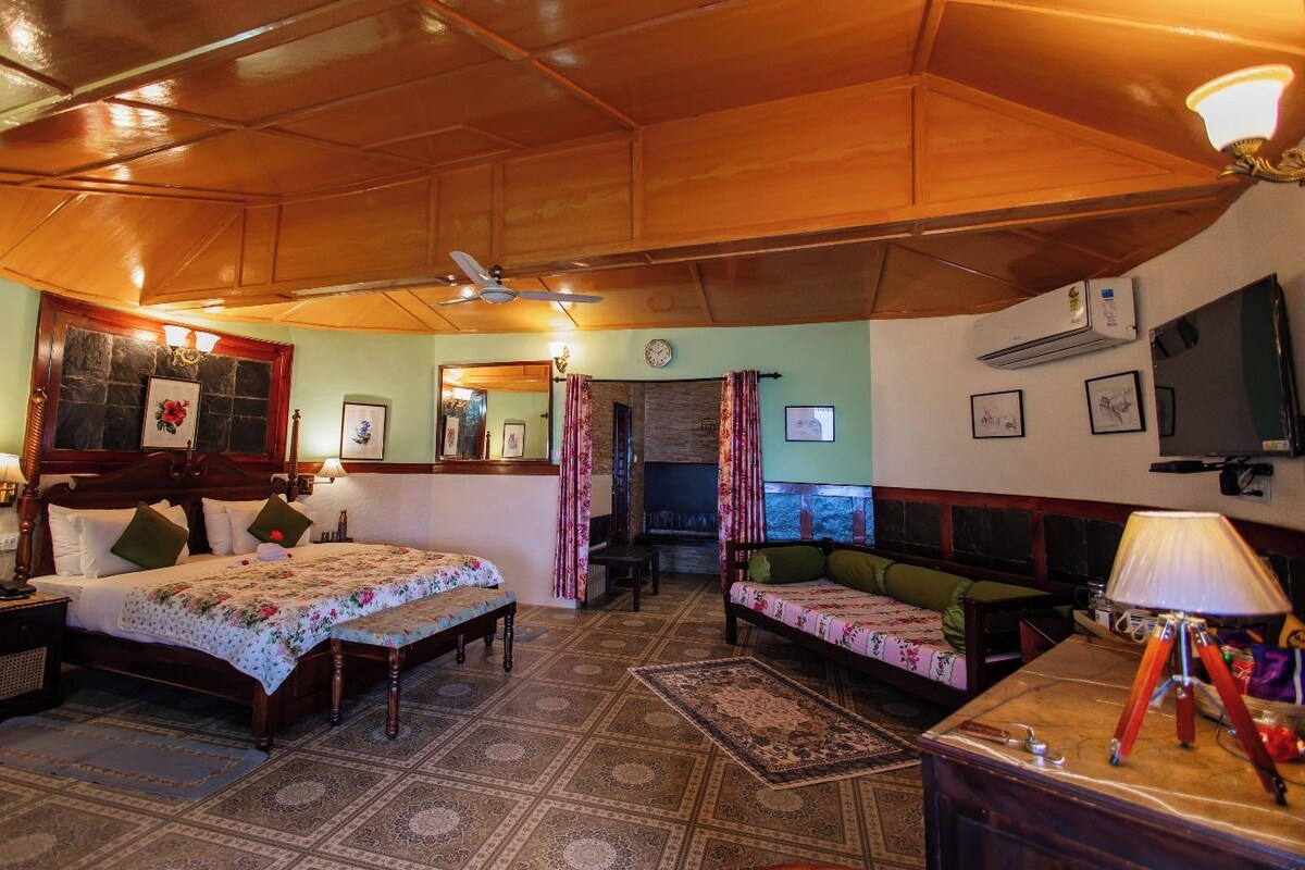 A spacious room with a large bed, a sofa, a desk, and a television.