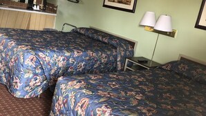 Habitación de hotel con dos camas, kitchenette, un cuadro enmarcado y una lámpara.
