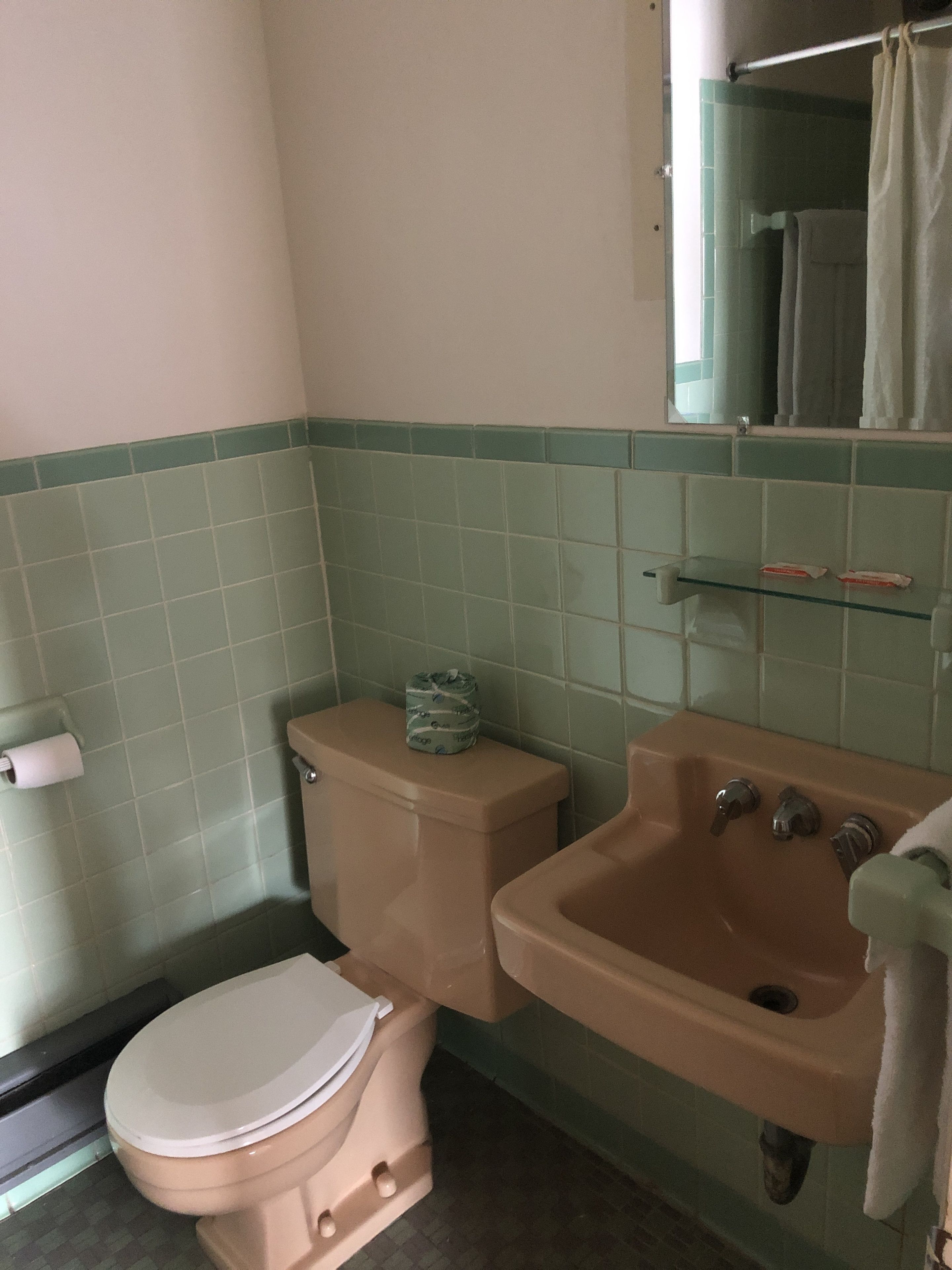 Un baño con inodoro, lavamanos y espejo.