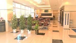 A spacious indoor area with rows of tables and chairs, large windows, and potted plants. - Toyoko Inn Urawa Misono Station (Saitama)