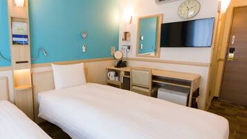 A hotel room with two beds, a desk, a mirror, a clock, and an air conditioning unit.
