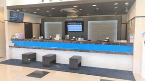 A hotel reception desk with a digital screen displaying room rates, a blue counter, and a tiled floor. - Toyoko Inn Urawa Misono Station (Saitama)