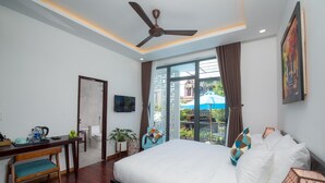 A hotel room with a bed, a desk, a chair, a ceiling fan, and a large window with a view of the outside. - La An Homestay (Da Nang)
