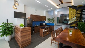 A modern kitchen with wooden cabinets, a built-in oven, and a dining area with a large wooden table and chairs. - La An Homestay (Da Nang)
