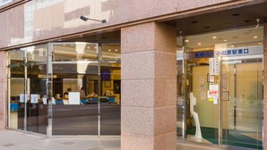A hotel entrance with a reception desk, glass doors, and a sign in a foreign language. - Toyoko Inn Odawara Station (Odawara)