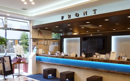 A reception area with a blue counter, a sign reading "FRONT", and a logo on the floor.