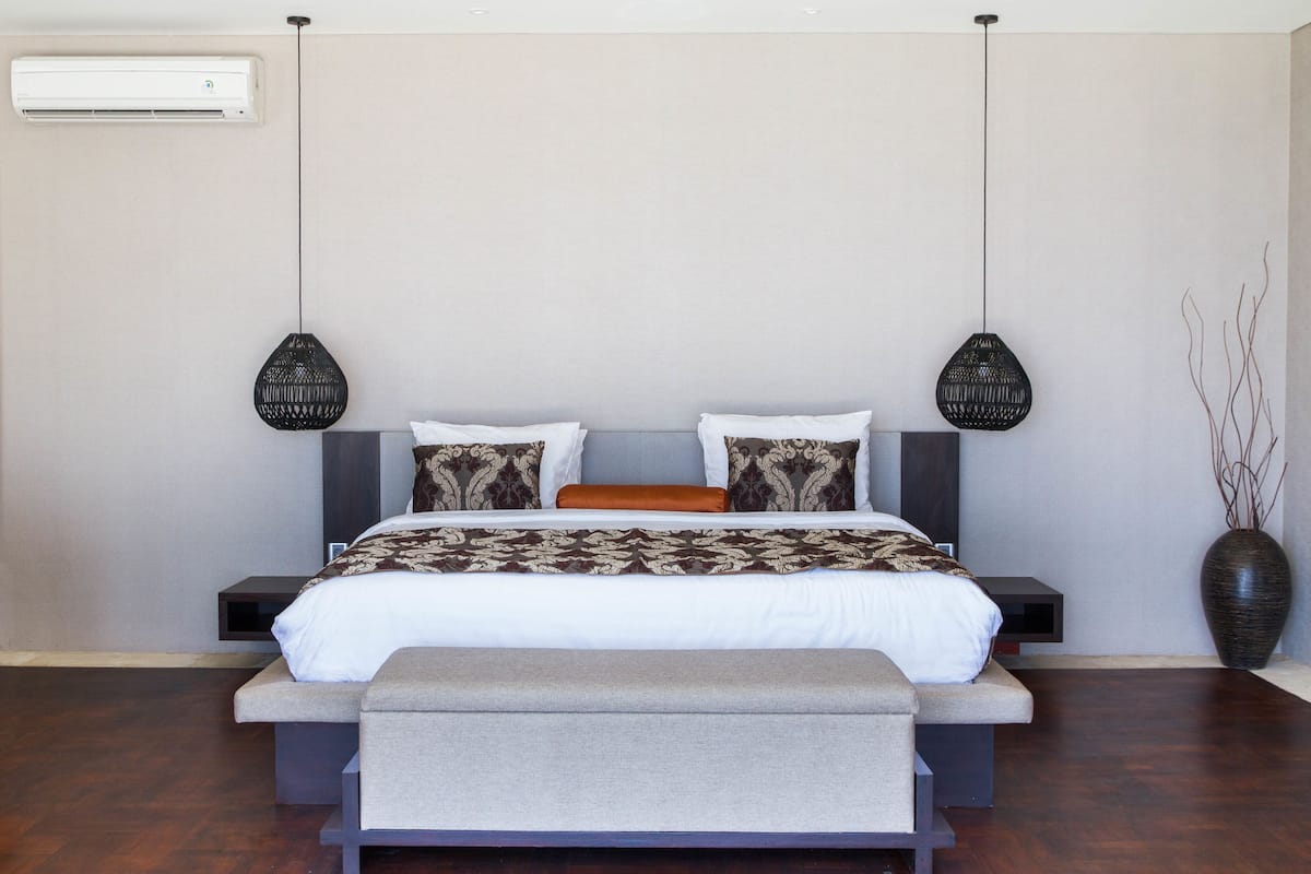 A modern bedroom with a bed, bedside tables, a bench, and a large vase.