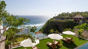 A poolside area with lounge chairs and umbrellas, overlooking a cliff and ocean. - Villa Maiara (Ungasan)