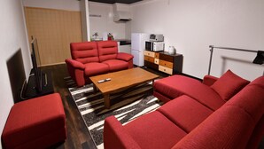 A compact living space with a sofa set, a coffee table, a kitchen area with a microwave and refrigerator, and a television. - Machi de kurasu Tengachaya-2 (Osaka)