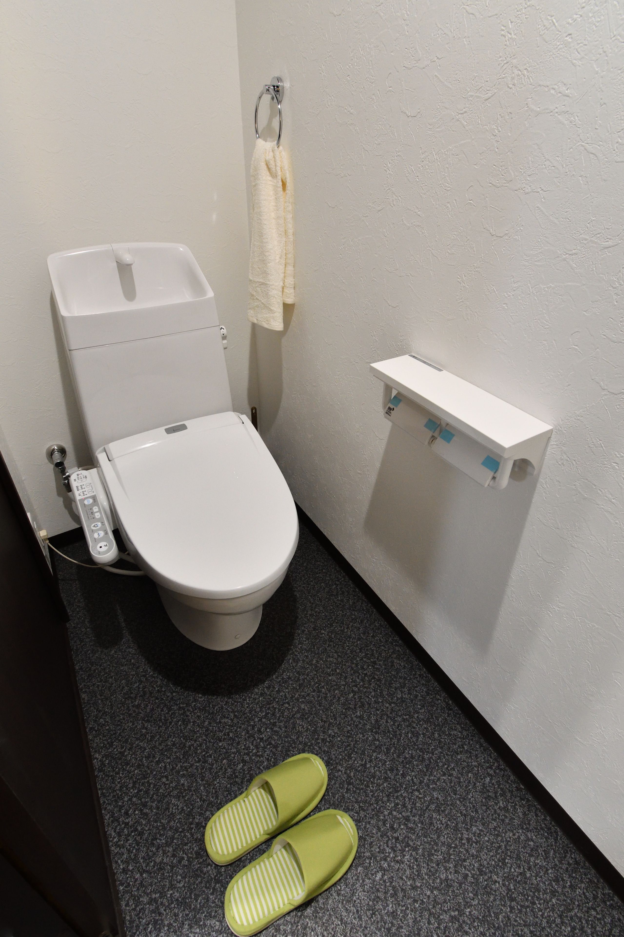 A small bathroom with a toilet, a towel rack, and a shelf.