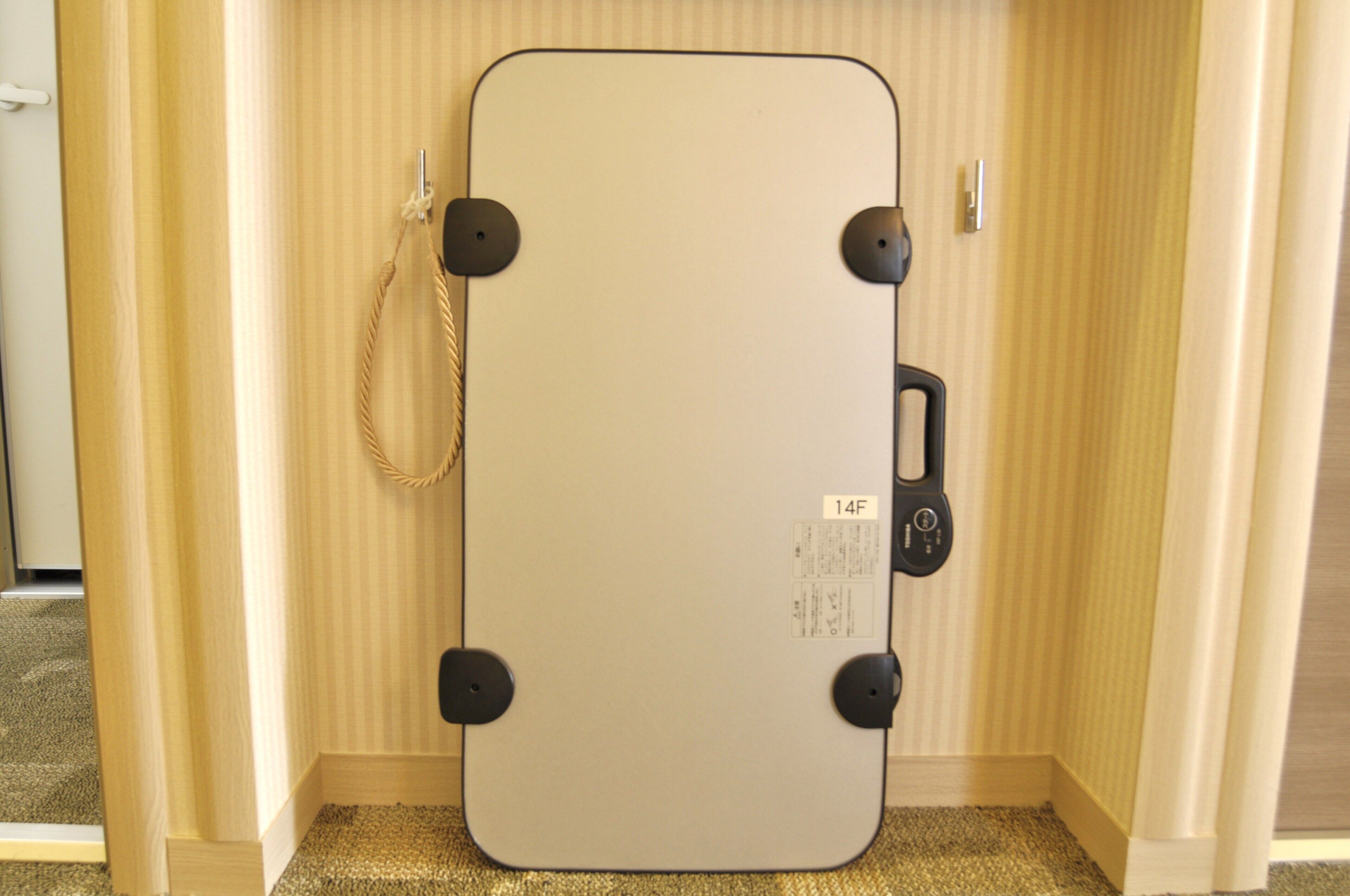 A room with a large, light-colored, rectangular mirror with a black frame and a cord hanging from it.