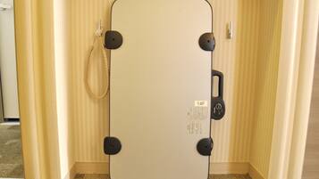 A room with a large, light-colored, rectangular mirror with a black frame and a cord hanging from it.