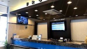 A hotel reception area with a marble counter, a television displaying information, and a sign above the counter reading "FRONT".