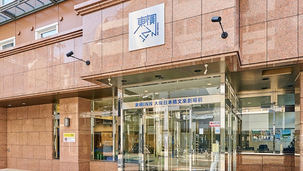 A building entrance with a sign indicating a location in Osaka, Japan.