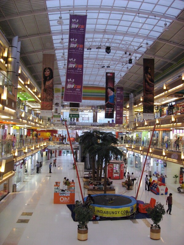 A multi-level shopping mall with a central atrium, multiple floors, and a variety of stores and kiosks. - Hotel Suvidha (Ahmedabad)