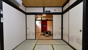 Una habitació japonesa tradicional amb fons de tatami, portes corredisses i una taula petita amb coixins.