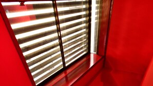 Un interior vermell amb una finestra i una petita escala.