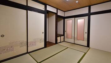 A traditional Japanese room with tatami flooring, sliding doors, and a wooden ceiling.