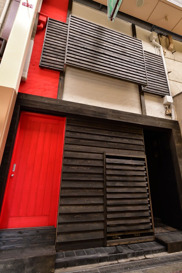 A building with a red door and a black awning. - Machi de kurasu Tengachaya-3 (Osaka)