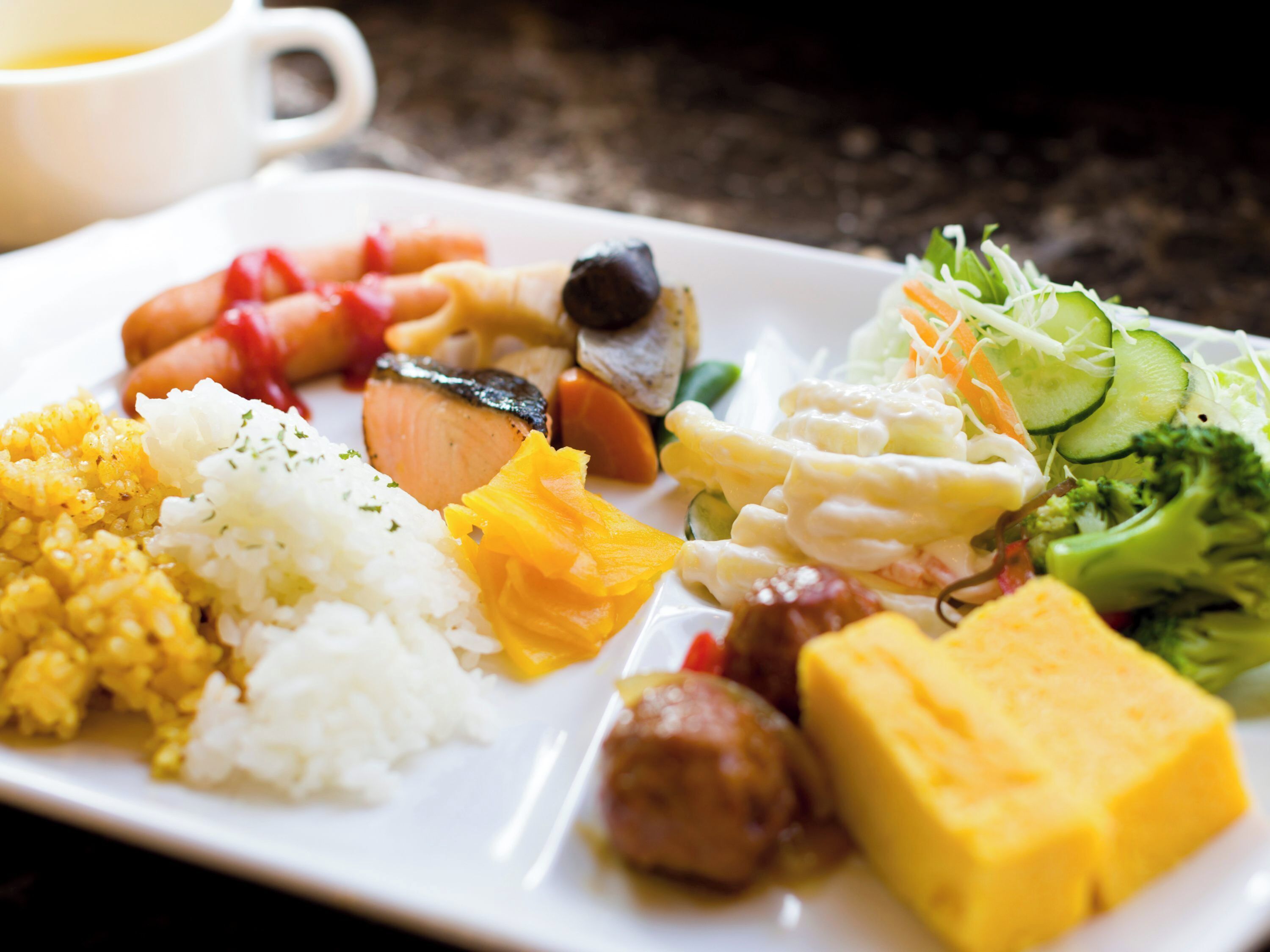 Un plato de comida con arroz, verduras y diversos tipos de carne.