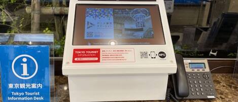 Un bureau d’information touristique à Tokyo, équipé d’un écran numérique, d’un téléphone et d’un code QR.