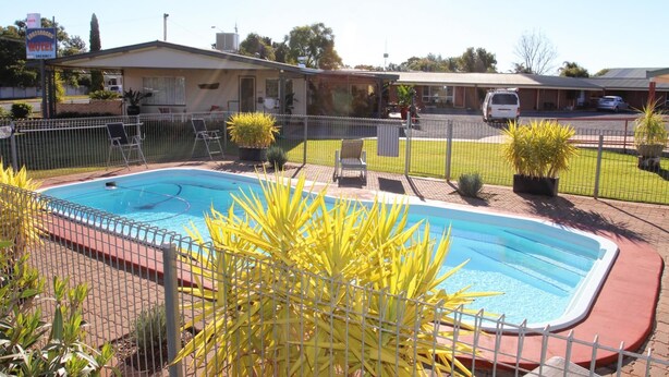 Un motel doté d’une piscine, d’un espace clôturé et de quelques plantes en pot.