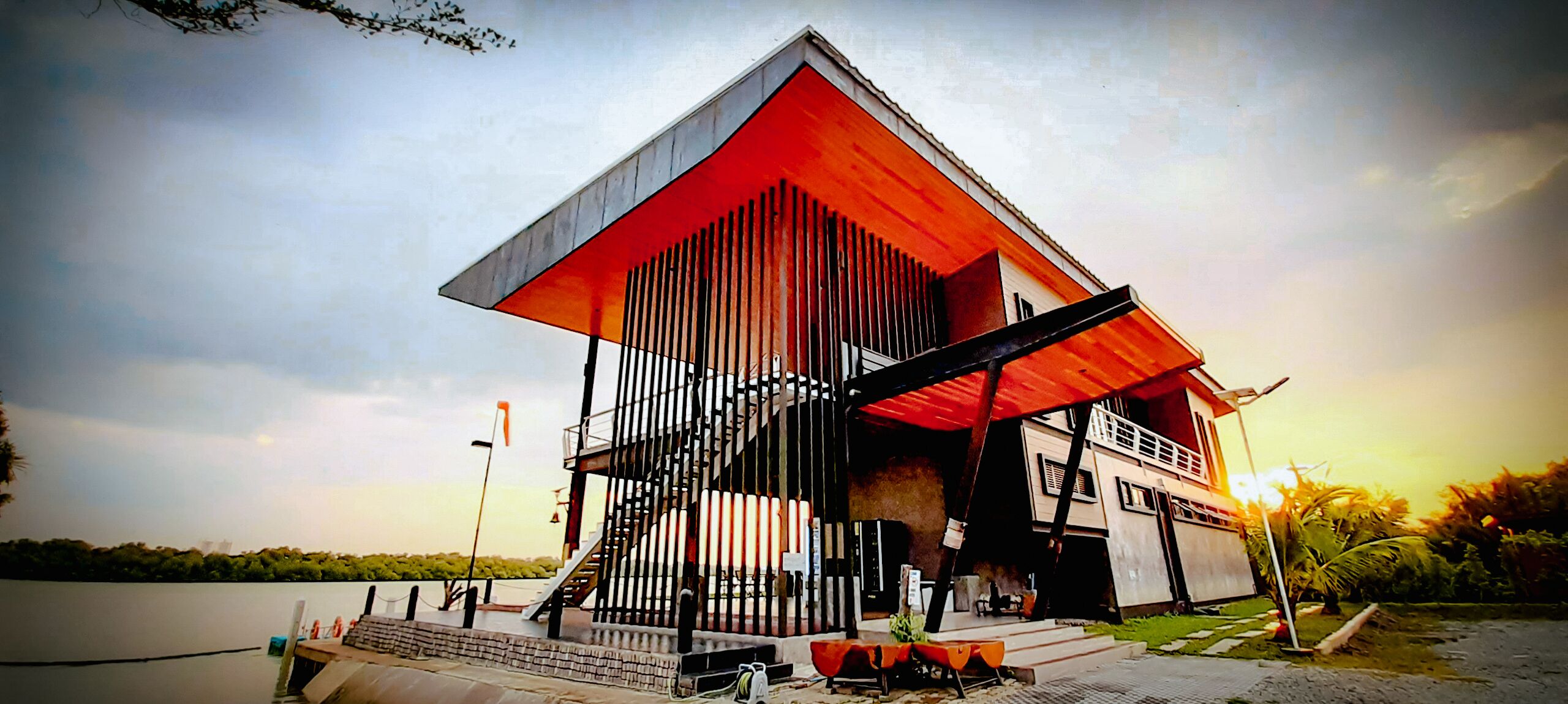 Un edificio moderno con techo inclinado, una escalera que lleva a un nivel superior y vista al agua.