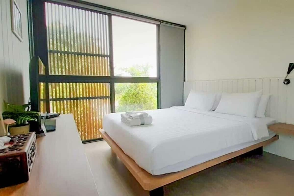 Een moderne slaapkamer met een groot bed, een bureau en een raam met zonwering.