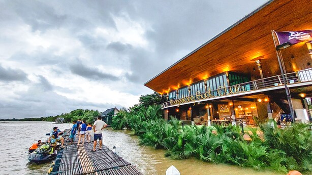 Een gebouw aan het water met een houten gevel en een overdekt terras.