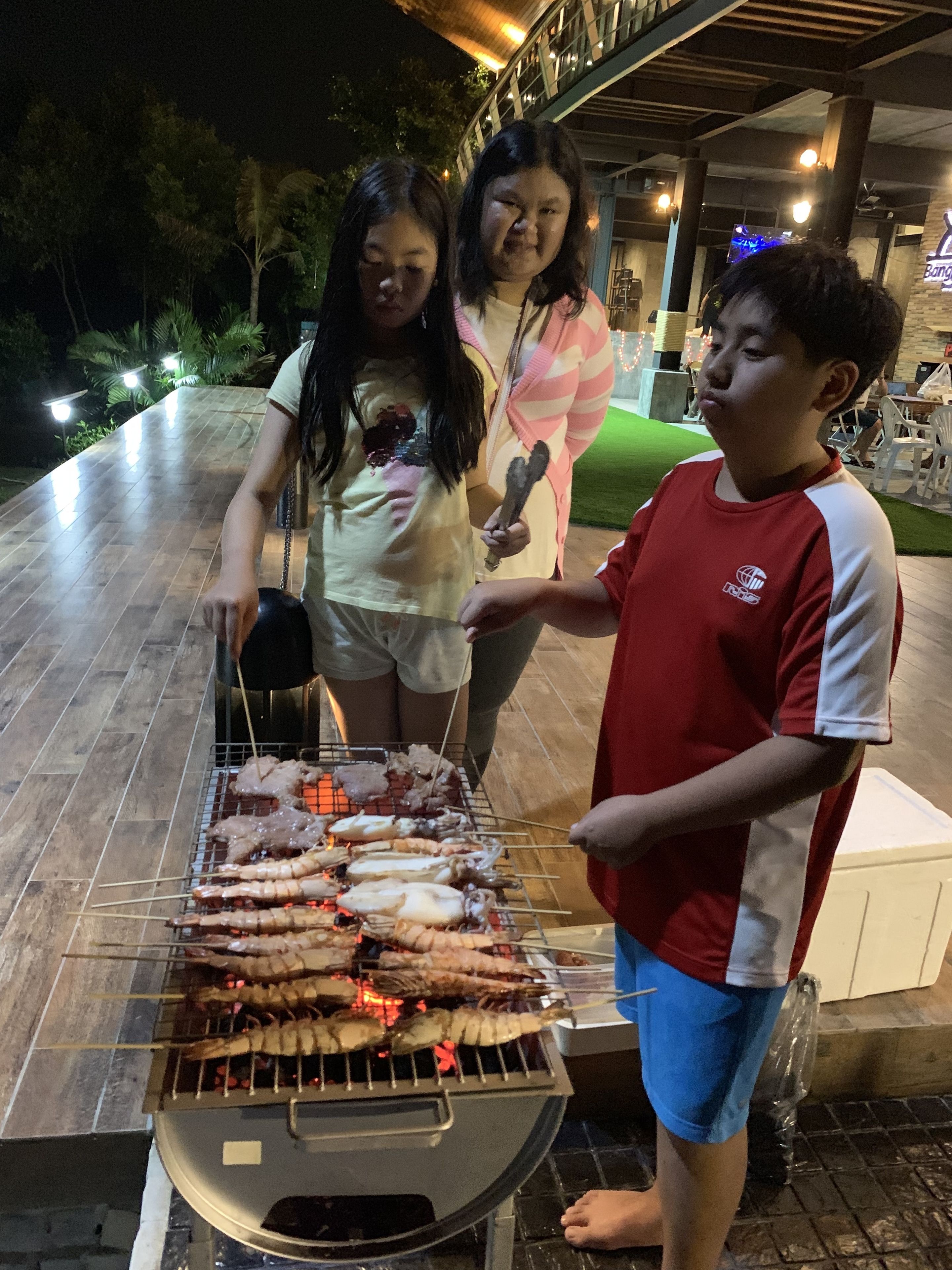 A group of people grilling seafood at an outdoor barbecue.