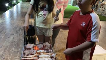 A group of people grilling seafood at an outdoor barbecue.