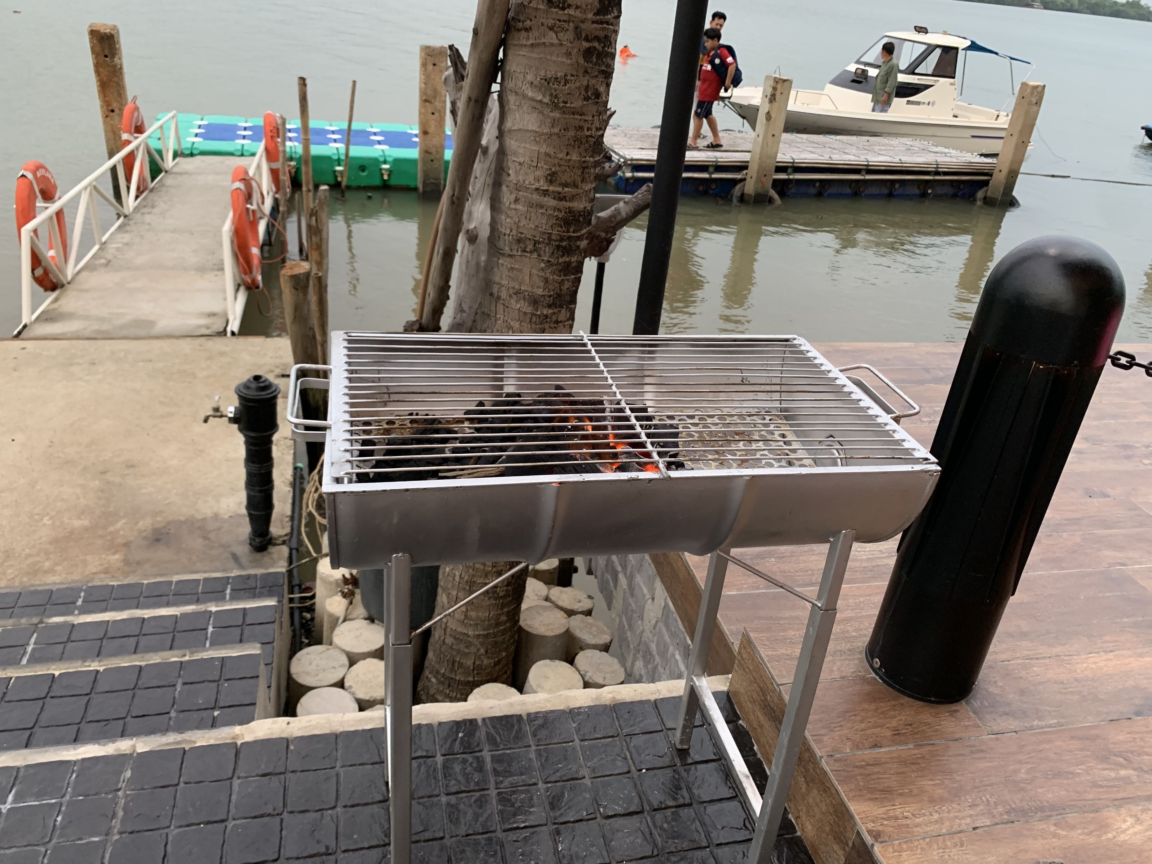 Un barbecue installé sur un quai, avec un bateau en arrière-plan.