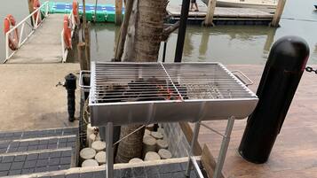 Un barbecue installé sur un quai, avec un bateau en arrière-plan.