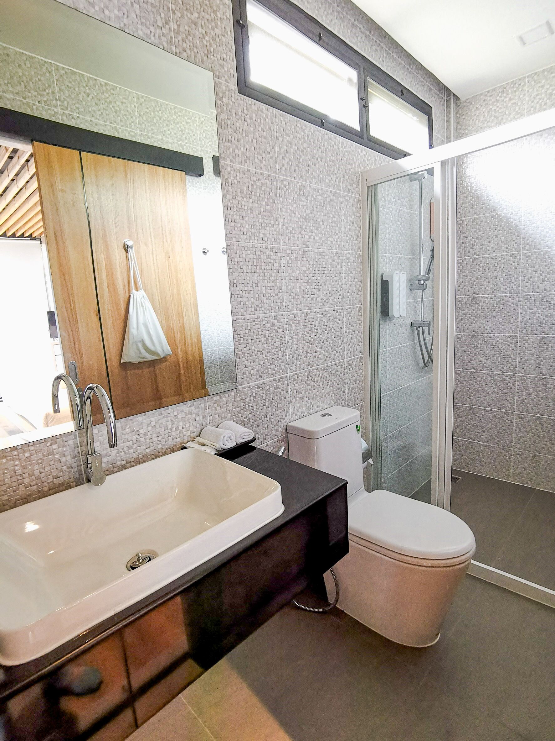 Un baño moderno con un lavamanos grande, un inodoro y una mampara de cristal para la ducha.