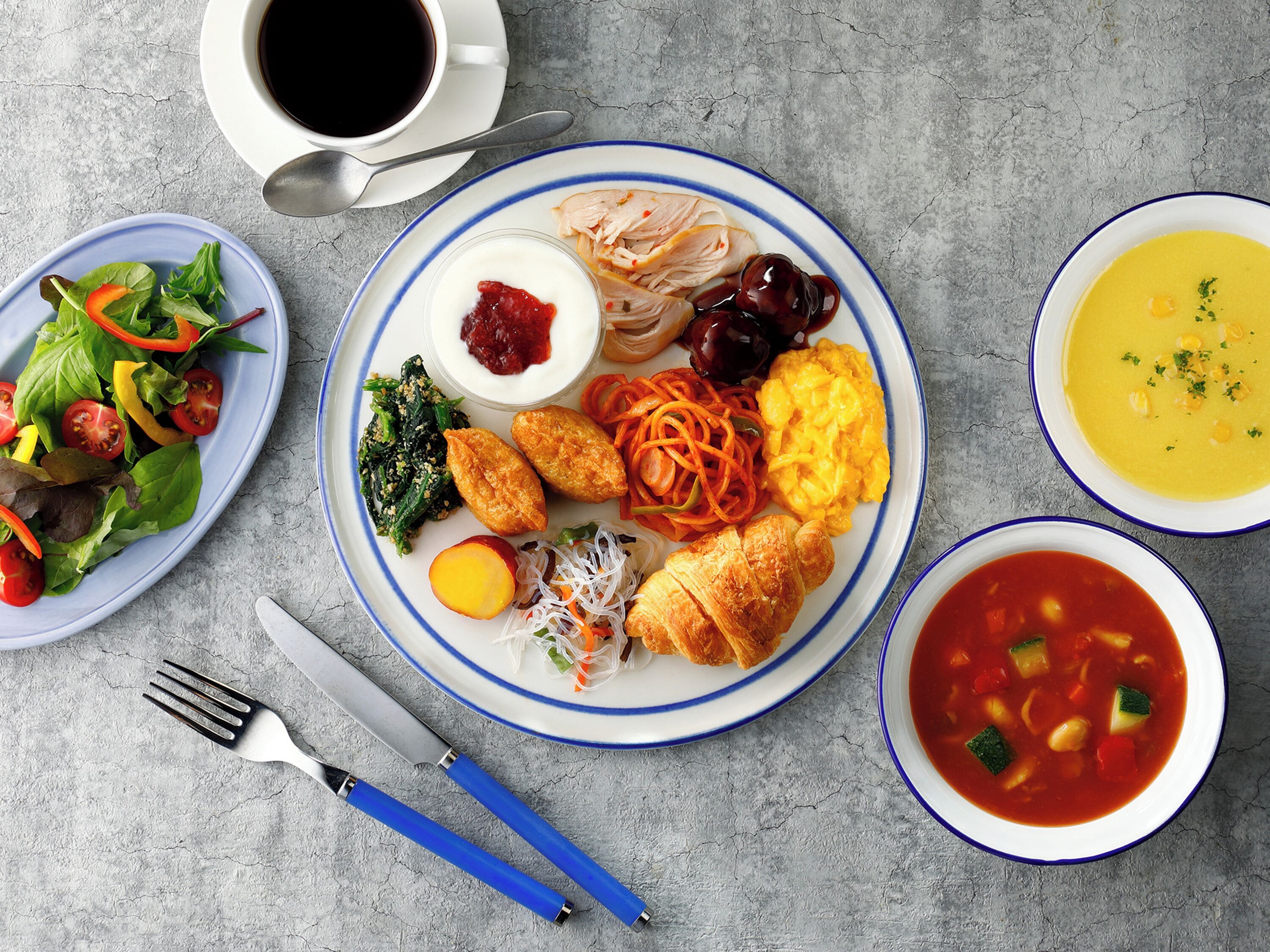 Una mesa con diversos platos, incluyendo una ensalada, un plato de huevos, verduras y un tazón de sopa.