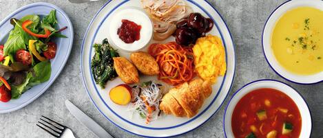 Una mesa con diversos platos, incluyendo una ensalada, un plato de huevos, verduras y un tazón de sopa.