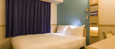 Habitación de hotel con cama, escritorio, reloj y teléfono instalado en la pared.