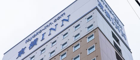 A building with a sign reading "Toyoko Inn" and a website address "toyoko-inn.com".