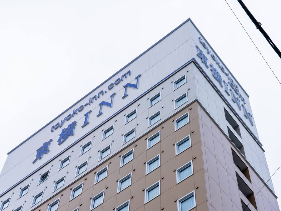 Ein Gebäude mit einem Schild, auf dem „Toyoko Inn“ steht, und einer Website-Adresse „toyoko-inn.com“.
